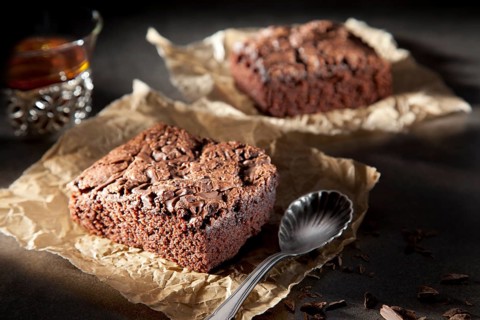 Two brownies with chocolate sauce on paper with spoon and tea