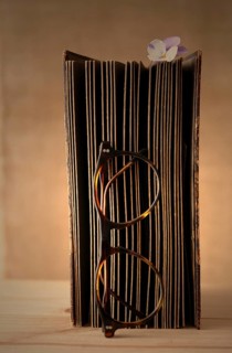 Old book with reading glasses and a horned violet