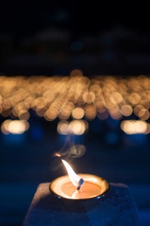 Burning candle with many lights in the background