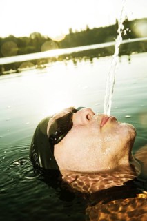 Man with swimming goggles spitting water in lake