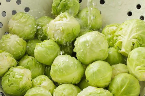 Brussels Sprouts in colander with running water