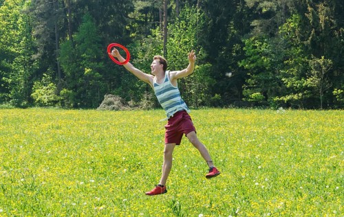 Young man catching frisbee in meadow