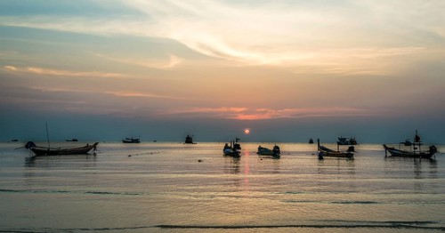 Long-tail boats in sea at sunset