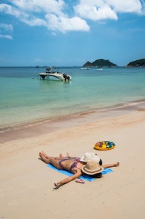 Mother and child lying on sandy beach