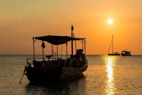 Fishing boat in sea at sunset