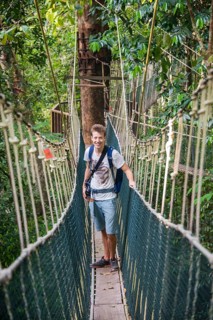 Young male tourist on a suspension bridge in the jungle