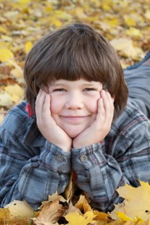 Little boy lying in autumn leaves