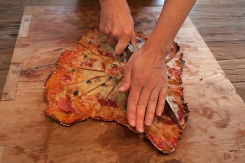 Stonebaked pizza being cut on a board
