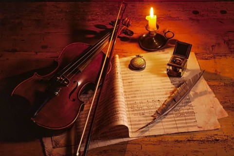 Violin with music sheet and quill by candlelight