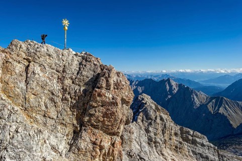 Mountaineer at the summit cross of the Zugspitze