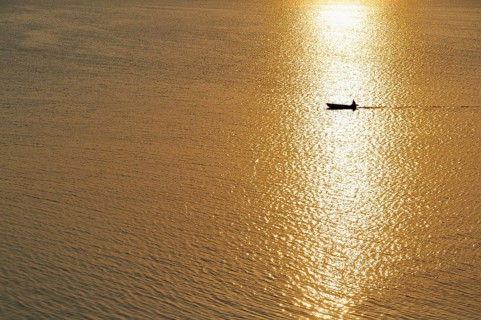 Fisherman in a motorboat at sunset