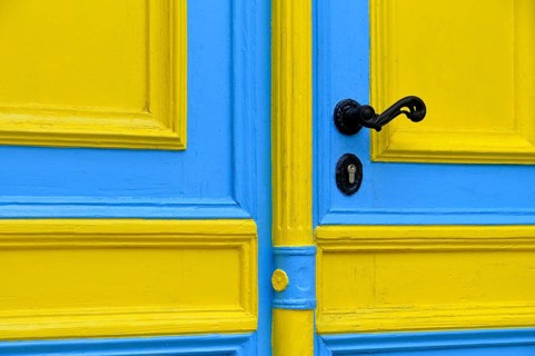 Blue and yellow painted front door with a black doorknob