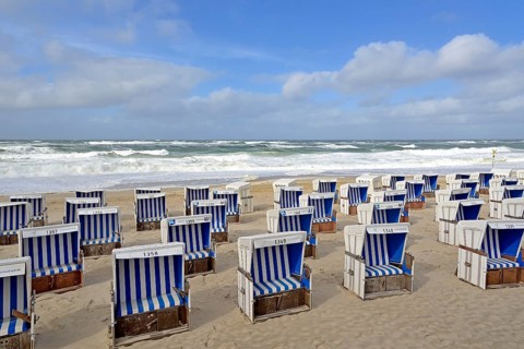 Sandy beach beach of Westerland with white-blue beach chairs at stormy North Sea