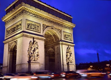 Illuminated Arc de Triomphe with traffic at night