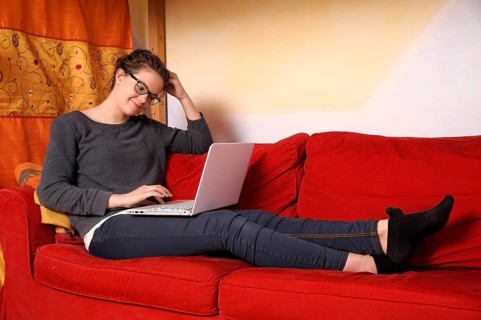 Teenager sitting with a laptop on a couch