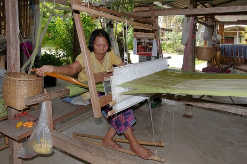 An elderly Tai Dam woman working on an old wooden loom