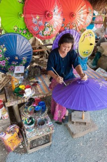 A woman is painting parasols at the umbrella village of Bo Sang