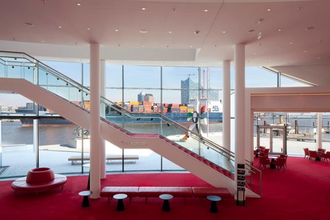 Stairs between the foyer levels overlooking a container ship off the city with the Elbe Philharmonic Hall
