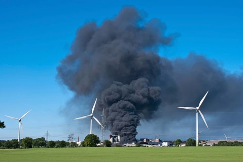 Major fire at waste recycling plant in the industrial area behind wind turbines