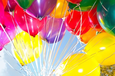 Colourful helium-filled balloons against a blue sky