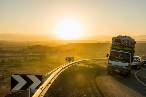 Loaded truck on curvy road in Dades Valley at sunset