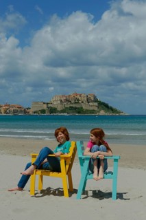 Children sitting in colorful beach chairs on the beach of Calvi