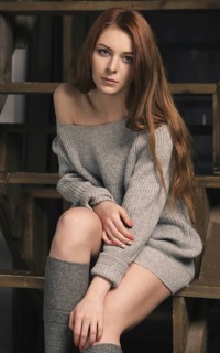 Young red-haired woman wearing a grey jumper