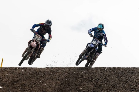 Two motorcyclists on motocross bikes riding on a dirt track