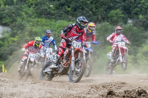 Group of motorcyclists on motocross bikes riding on a dirt track