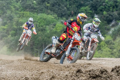 Group of motorcyclists on motocross bikes riding on a dirt track