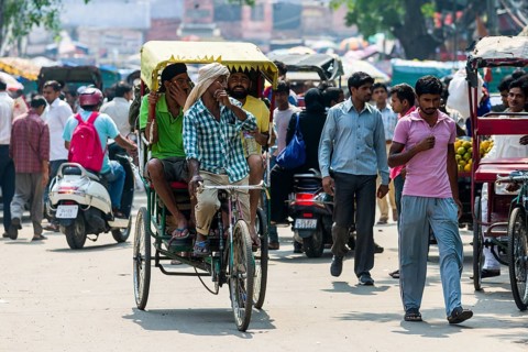 People and cycle rickshaws are moving through the streets of the suburb Old Delhi