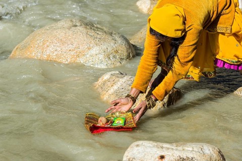 A female pilgrim at the banks of the river Ganges is praying