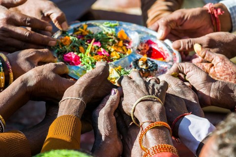 Many hands are holding a plate