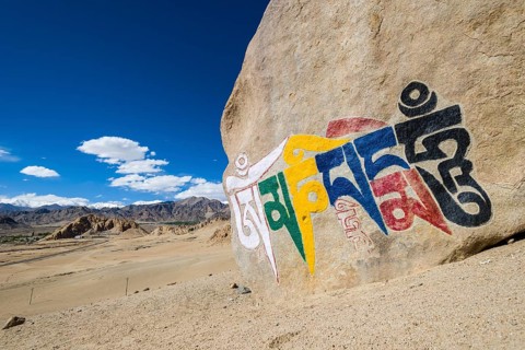 A big Tibetan Mani Stone with the Mantra "Om Mani Padme Hum" colorfully engraved on a hill above the Indus Valley