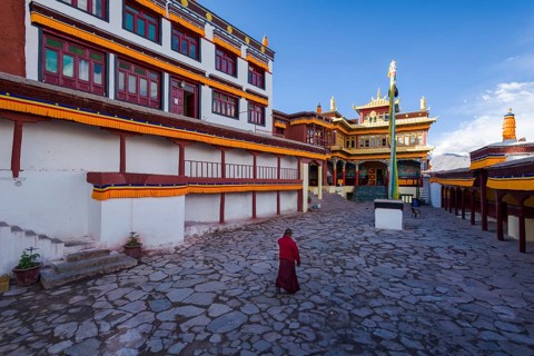A monk is walking in the inner courtyard of Matho Gompa