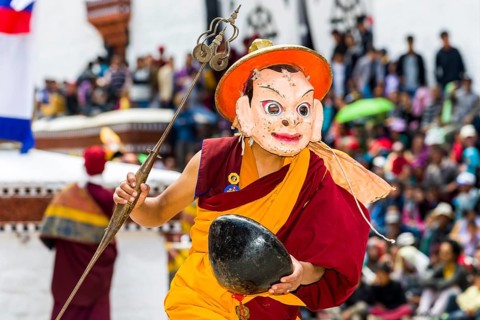 Monks with big wooden masks and colorful costumes are performing ritual dances at Hemis Festival in the courtyard of the monastery