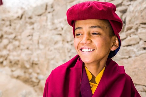 A portrait of a young monk of the Kagyu lineage of Buddhism in red clothes