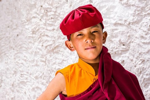 A portrait of a young monk of the Kagyu lineage of Buddhism in red clothes