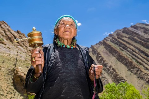 An old Ladakhi woman is turning a prayer wheel
