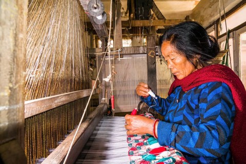 A woman is working on an old traditional loom