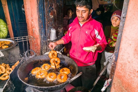 A man is frying doughnuts in a big pan for the typical nepali breakfast