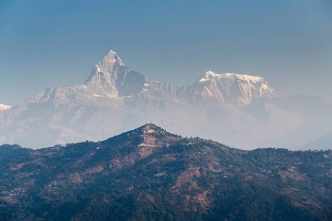Summits of Annapurna III and Machapuchare in the haze behind the Sarangkot mountain ridge