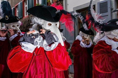 Many different groups of masked people walking through the streets of Basel