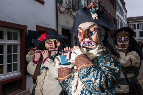 Many different groups of masked people walking through the streets of Basel