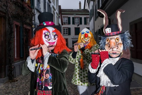 Many different groups of masked people walking through the streets of Basel