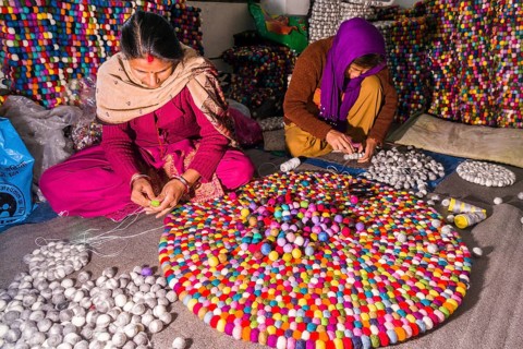 Women are producing a carpet from felt balls