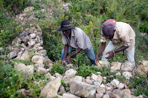 Men building walls with boulders to prevent erosion on deforested slopes