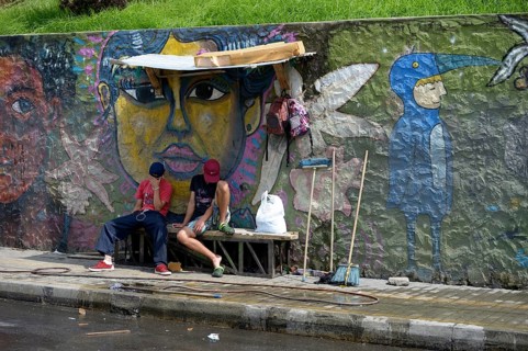Young gang members sitting in front of graffiti wall