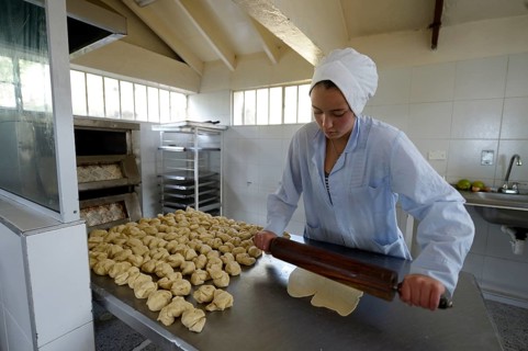 Teen rolling out dough in the bakery of a social project