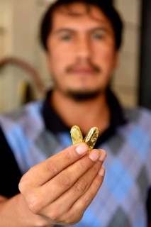Man holding two pieces of gold in shop